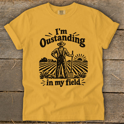 Yellow t-shirt with "I'm Oustanding in my field" graphic and farmer illustration.