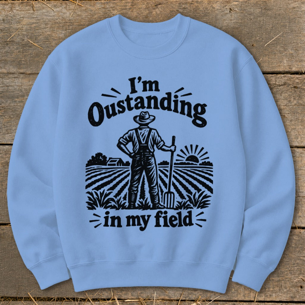 Light blue sweatshirt with black graphic saying "I'm Oustanding in my field" and a farmer illustration.