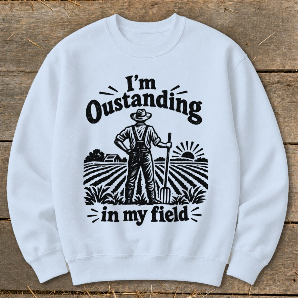 White sweatshirt with black graphic of farmer and text "I'm Oustanding in my field".