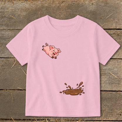 Pink t-shirt with a cartoon pig jumping over a mud puddle graphic.