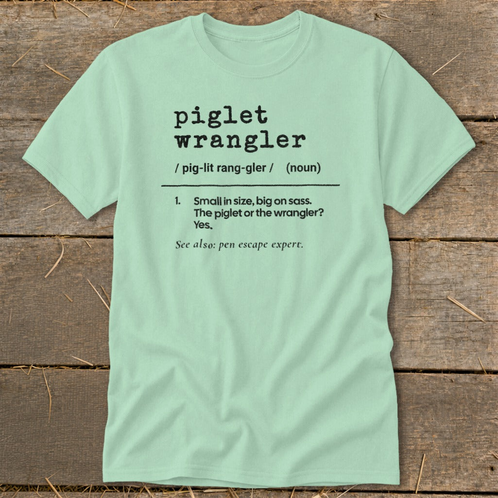 Light green t-shirt with "piglet wrangler" definition printed in black text.