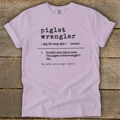 Light purple t-shirt with "piglet wrangler" definition and "pen escape expert" text.