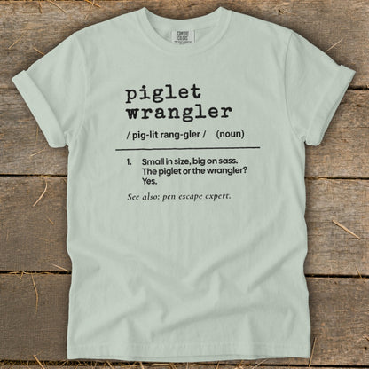 Light green t-shirt with "piglet wrangler" definition and "pen escape expert".
