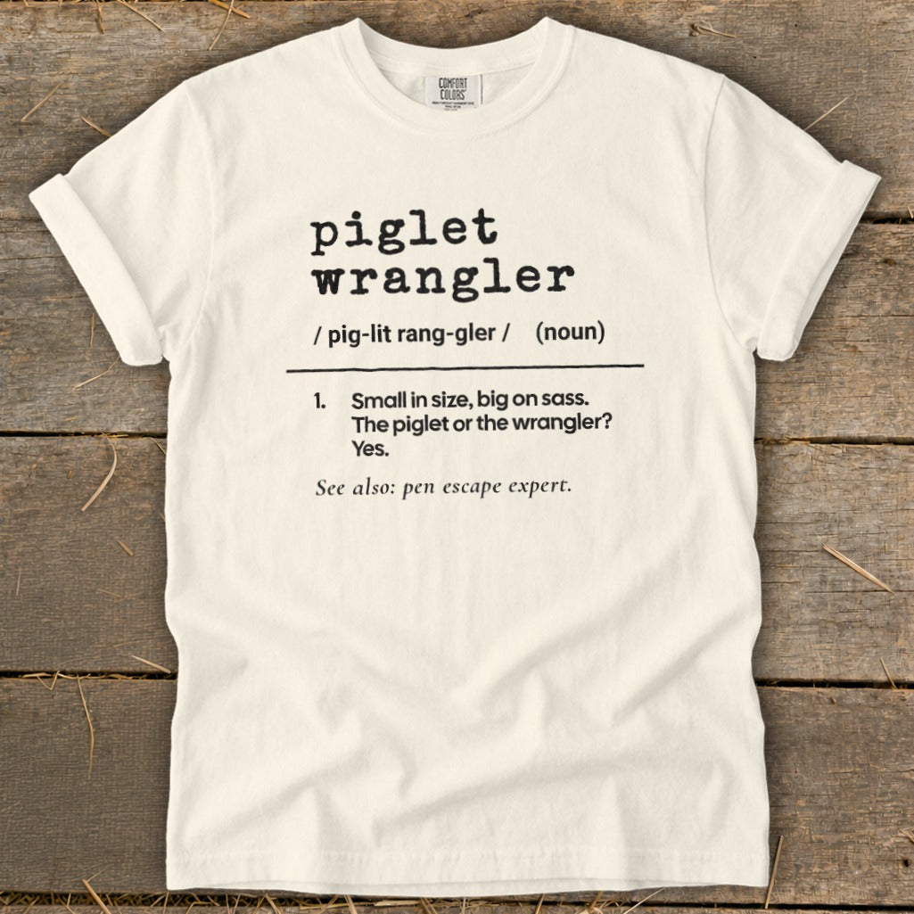 Cream t-shirt with black text defining "piglet wrangler" and "pen escape expert."