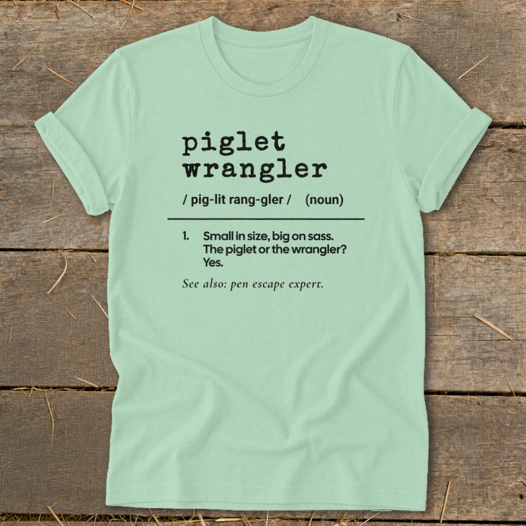 Light green t-shirt with "piglet wrangler" definition and "pen escape expert" text.