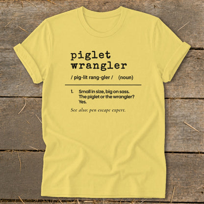 Yellow t-shirt with "piglet wrangler" definition and "pen escape expert."
