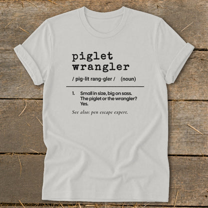 White t-shirt with "piglet wrangler" definition and "pen escape expert".