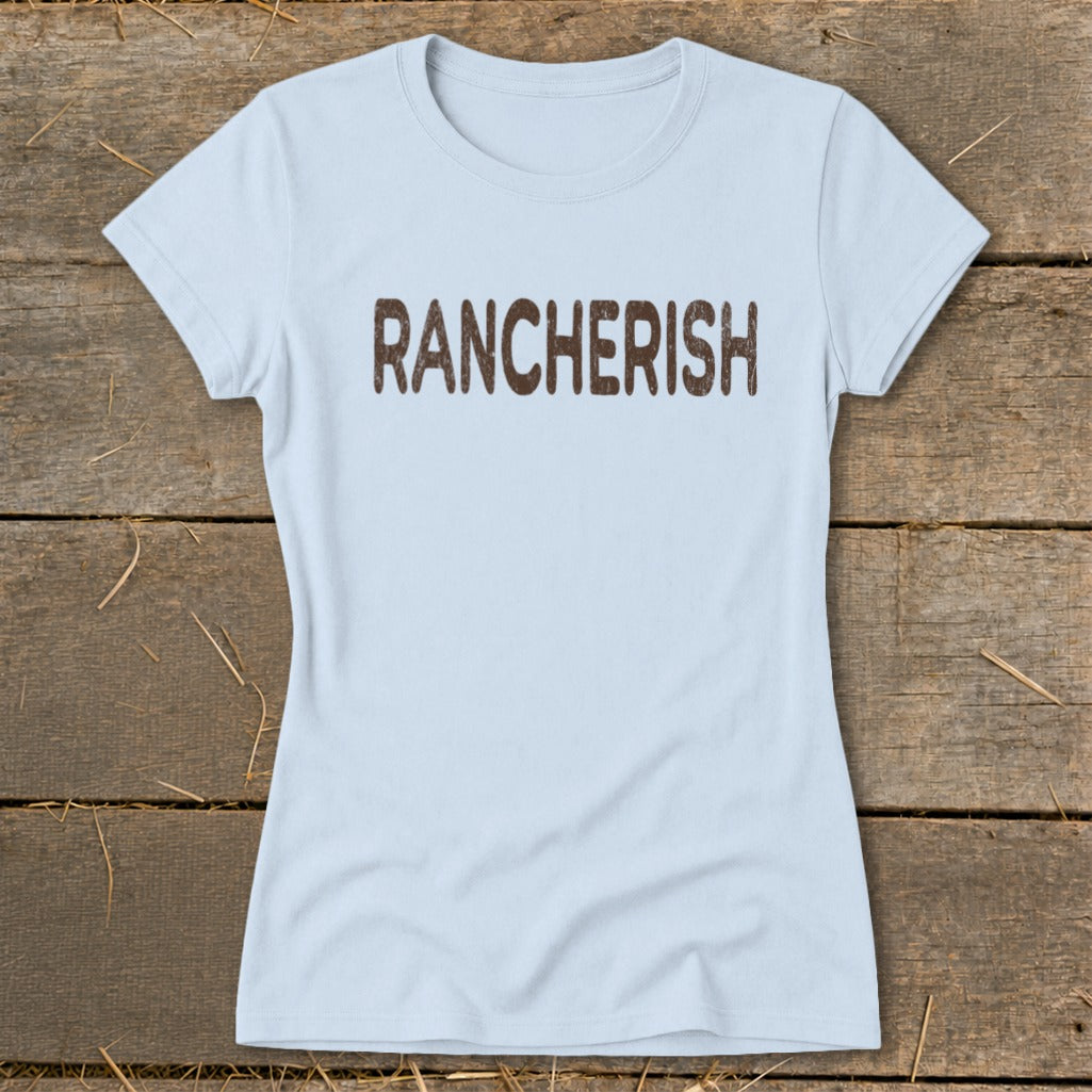 Light blue t-shirt with brown "RANCHERISH" text on a wooden background.