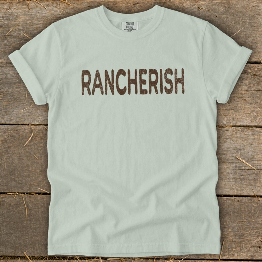 Light mint Comfort Colors t-shirt with brown "RANCHERISH" graphic.