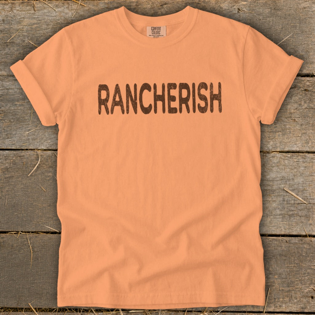 Orange Comfort Colors t-shirt with "RANCHERISH" printed in brown text.