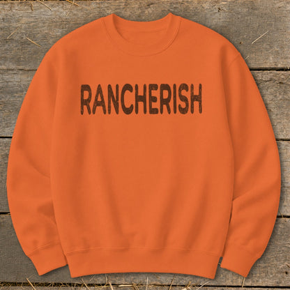 Orange crewneck sweatshirt with "RANCHERISH" in brown distressed lettering.
