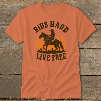 Orange t-shirt with cowboy silhouette riding horse, sunset and cacti, text "RIDE HARD LIVE FREE".