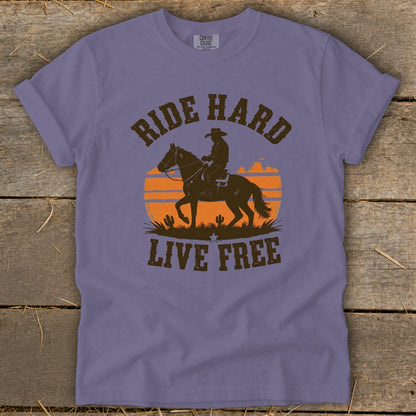 Lavender t-shirt with distressed graphic: cowboy on horse, sunset, and text "RIDE HARD LIVE FREE".