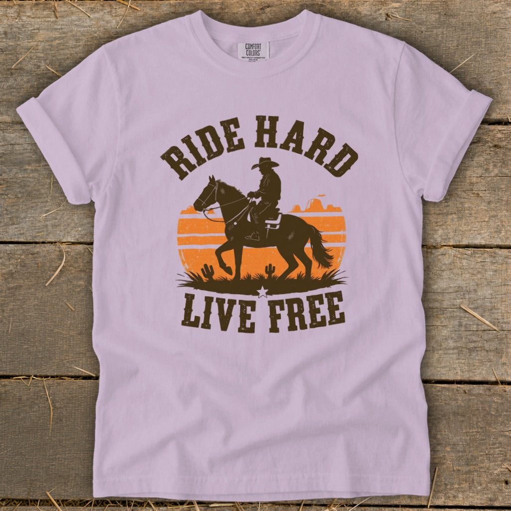 T-shirt with graphic of cowboy on horse, sunset, cactuses, and text "RIDE HARD LIVE FREE."