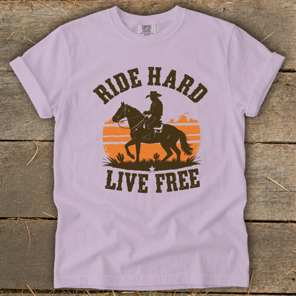 T-shirt with graphic of cowboy on horse, sunset, cactuses, and text "RIDE HARD LIVE FREE."