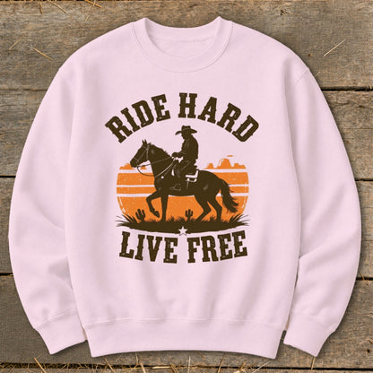 Pink sweatshirt with "Ride Hard Live Free" text and cowboy on horseback graphic.