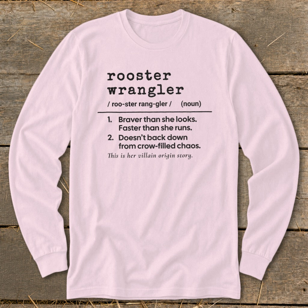Light pink long-sleeve t-shirt with black dictionary-style text defining rooster wrangler laid flat on wood.