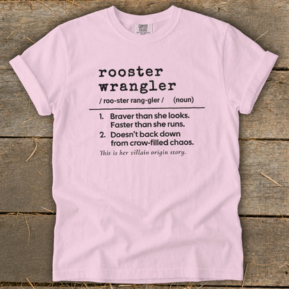 Pink t-shirt with "rooster wrangler" definition: "Braver than she looks. Faster than she runs. Doesn't back down from crow-filled chaos. This is her villain origin story."