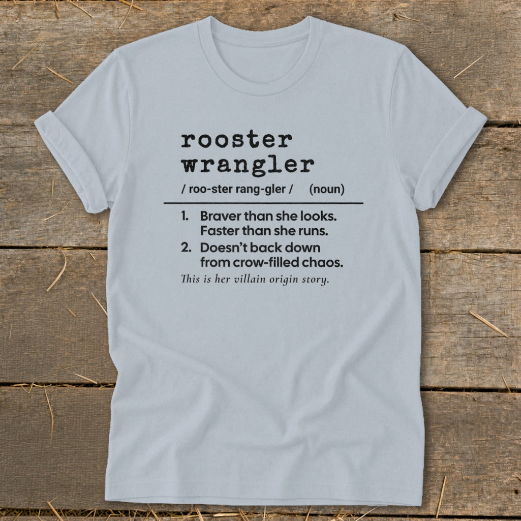Light gray t-shirt with black text defining "rooster wrangler" and "villain origin story."