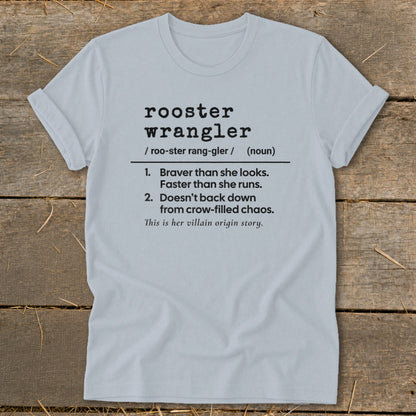 Light gray t-shirt with black text defining "rooster wrangler" and "villain origin story."