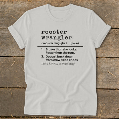 White t-shirt with black text defining "rooster wrangler" as a noun.