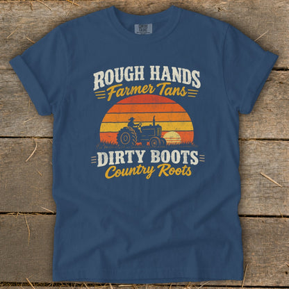 Blue t-shirt featuring a retro graphic of a tractor against a sunset and text reading Rough Hands Farmer Tans Dirty Boots Country Roots.