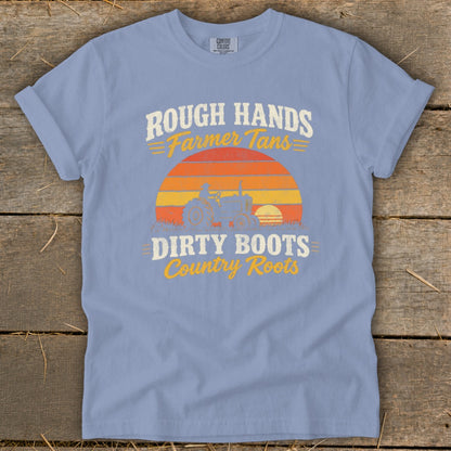 Periwinkle blue t-shirt with a vintage tractor graphic and the text Rough Hands Farmer Tans Dirty Boots Country Roots.