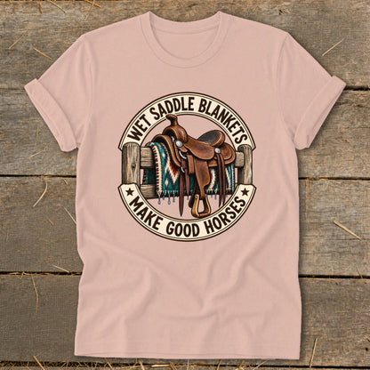 T-shirt with graphic of saddle and blanket on fence, "Wet Saddle Blankets Make Good Horses" text.