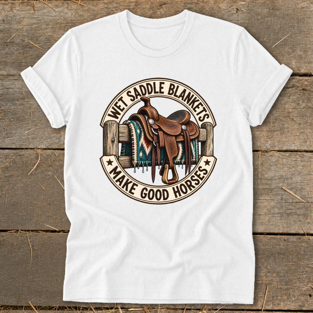 White t-shirt with a saddle and blanket on a fence, text reads "WET SADDLE BLANKETS MAKE GOOD HORSES".