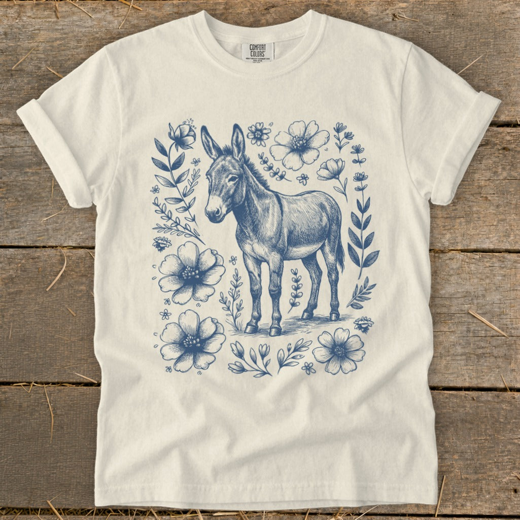 Cream t-shirt with blue sketch of a donkey surrounded by flowers and leaves.