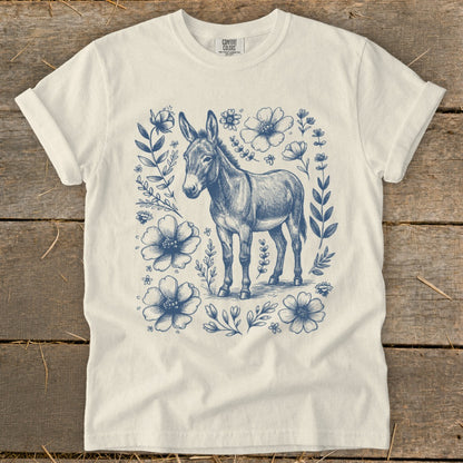 Cream t-shirt with blue sketch of a donkey surrounded by flowers and leaves.