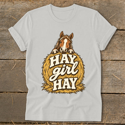 Light gray t-shirt with a brown horse peeking over a hay bale with text.