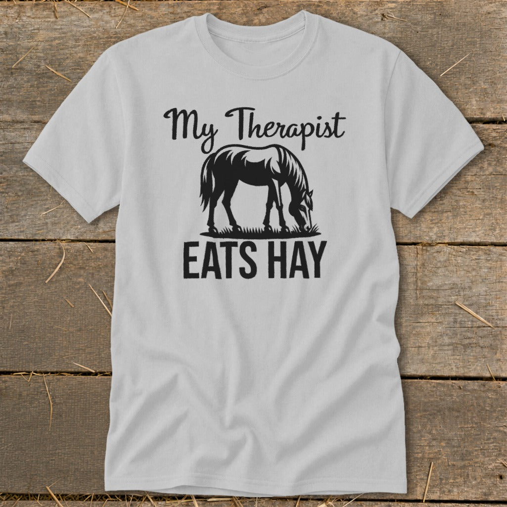Light gray t-shirt with black text and horse graphic reading "My Therapist Eats Hay".