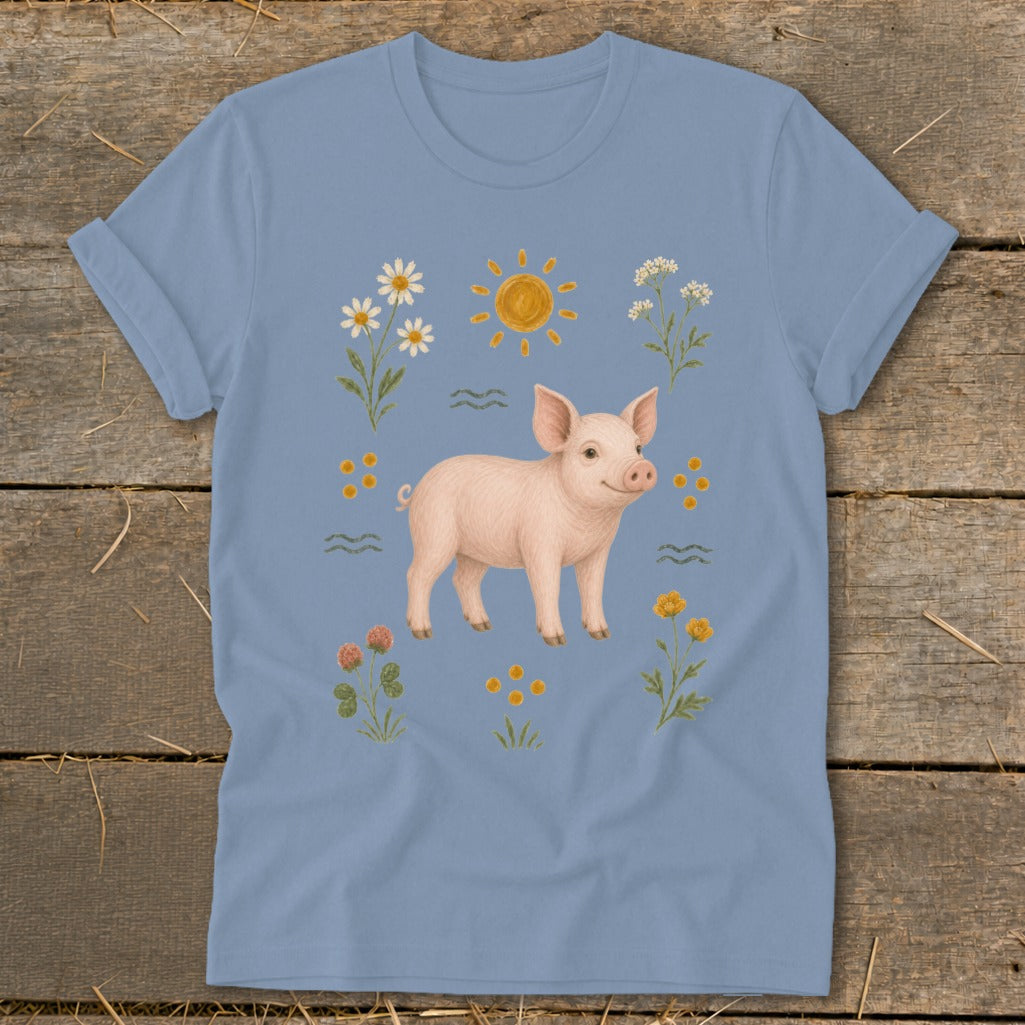 Light blue t-shirt with a cheerful piglet illustration surrounded by flowers and the sun.