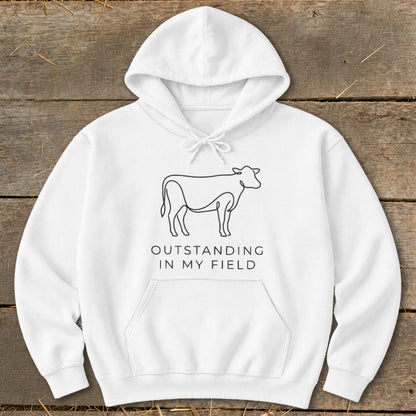 White hoodie with a line drawing of a cow and text "OUTSTANDING IN MY FIELD".