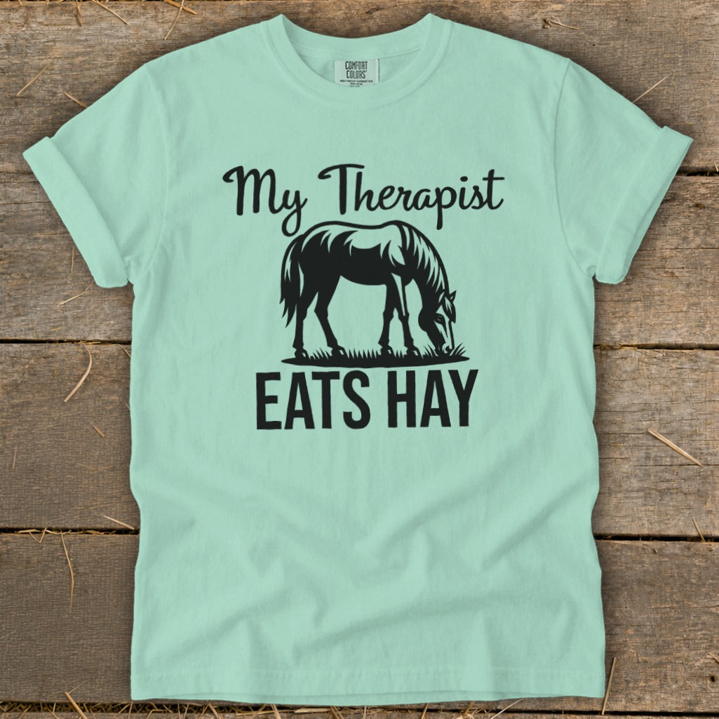 Mint t-shirt with black graphic: horse eating hay, text "My Therapist EATS HAY".