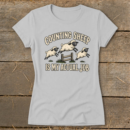 Light gray t-shirt with three sheep jumping over a fence with text "COUNTING SHEEP IS MY ACTUAL JOB".