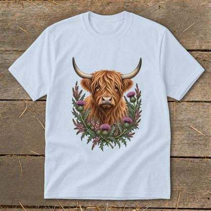 Highland cow illustration with thistles on a light blue t-shirt.