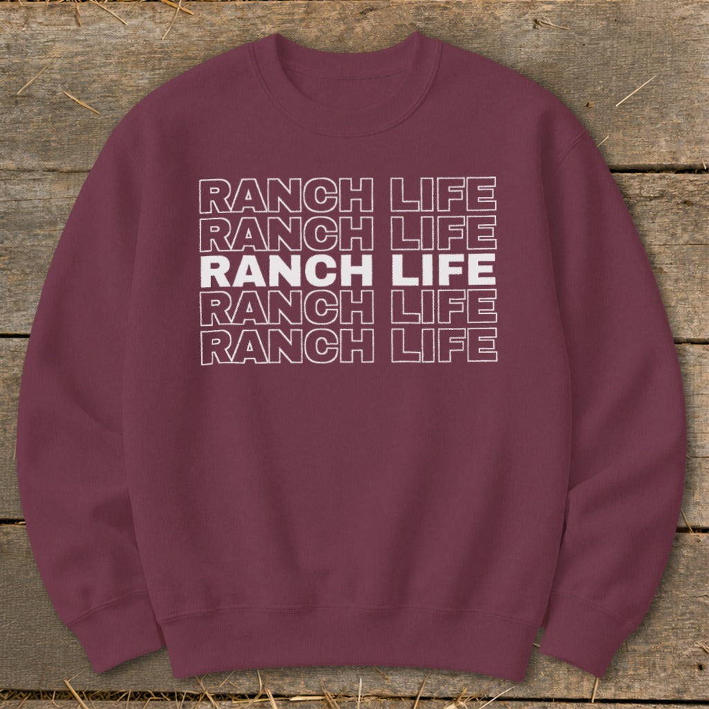 Maroon crewneck sweatshirt featuring five stacked lines of Ranch Life text on a wooden background.