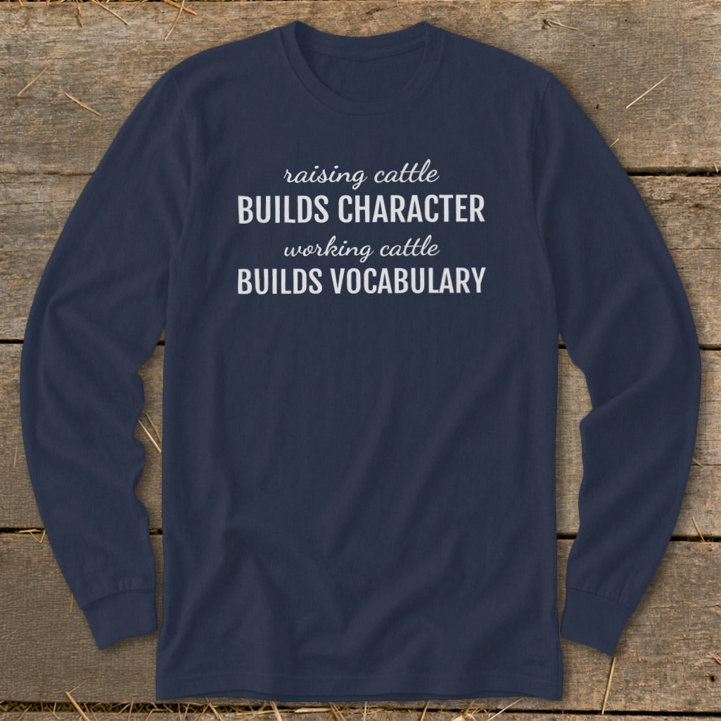 Navy long-sleeve shirt with white text: "raising cattle BUILDS CHARACTER, working cattle BUILDS VOCABULARY."