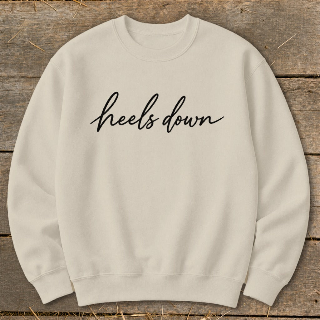 Cream crewneck sweatshirt with "heels down" printed in black cursive.