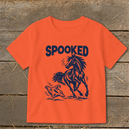 Orange t-shirt with navy text "SPOOKED" above a startled horse facing a ghost.