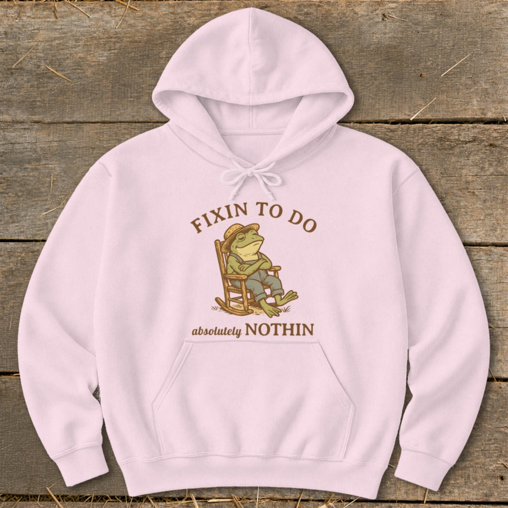 Pink hoodie with cartoon frog in rocking chair, text "FIXIN TO DO absolutely NOTHIN".