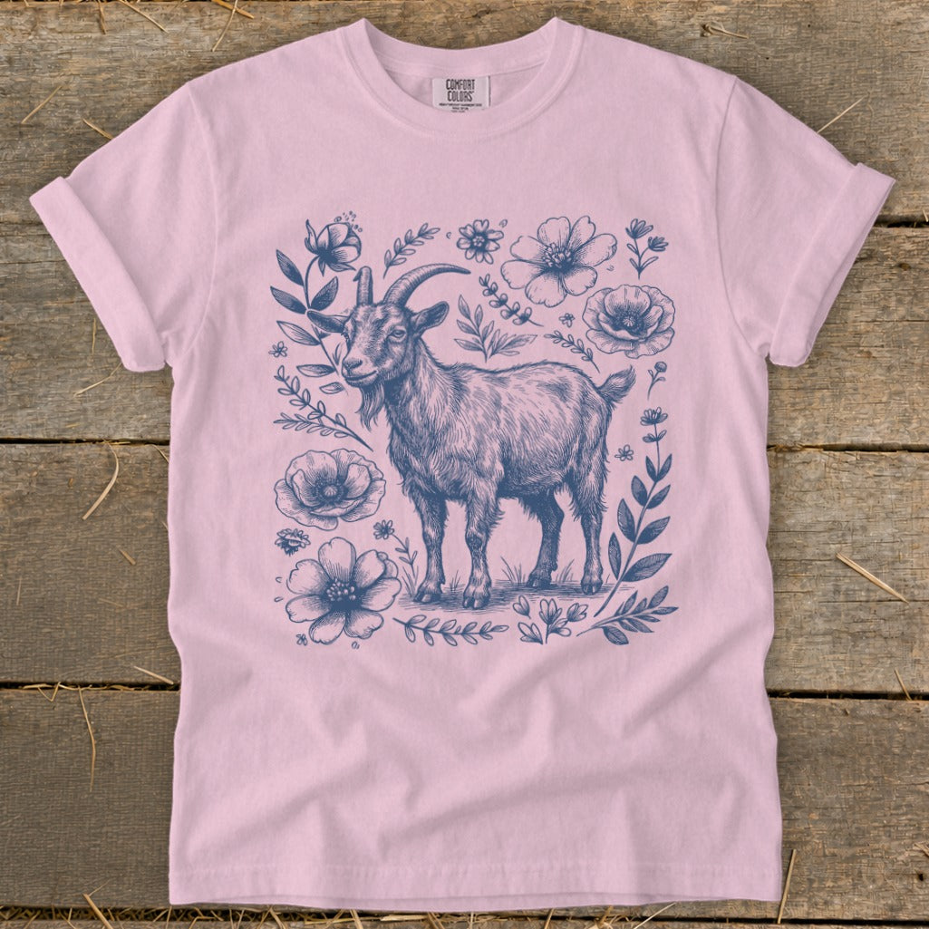 Pink t-shirt with a blue sketch of a goat surrounded by flowers and leaves.