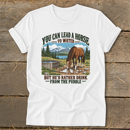 A white t-shirt featuring a graphic illustration of a horse drinking from a puddle with mountains in the background.