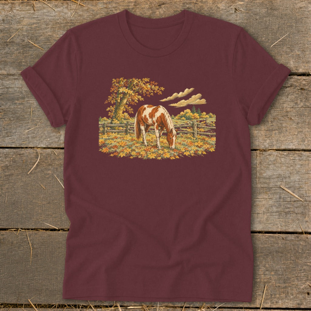 Maroon t-shirt with a brown and white horse grazing in an autumn field.
