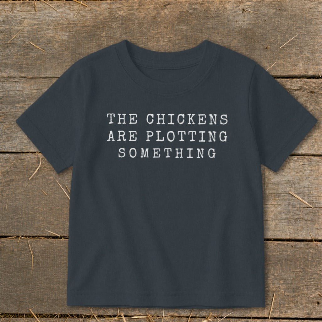 Dark gray t-shirt with white text "THE CHICKENS ARE PLOTTING SOMETHING."
