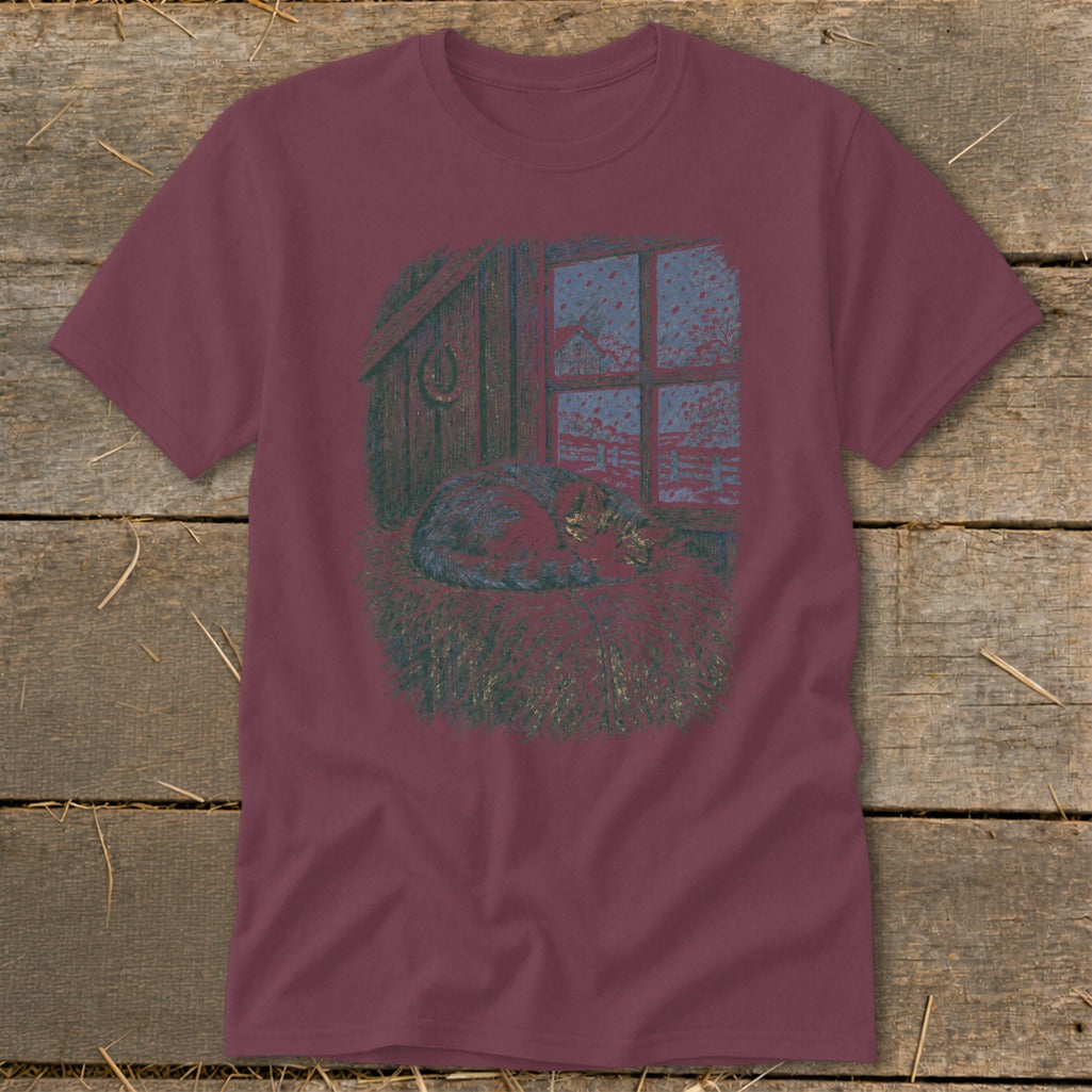 T-shirt graphic: cat sleeping in hay in front of a window with a winter scene.