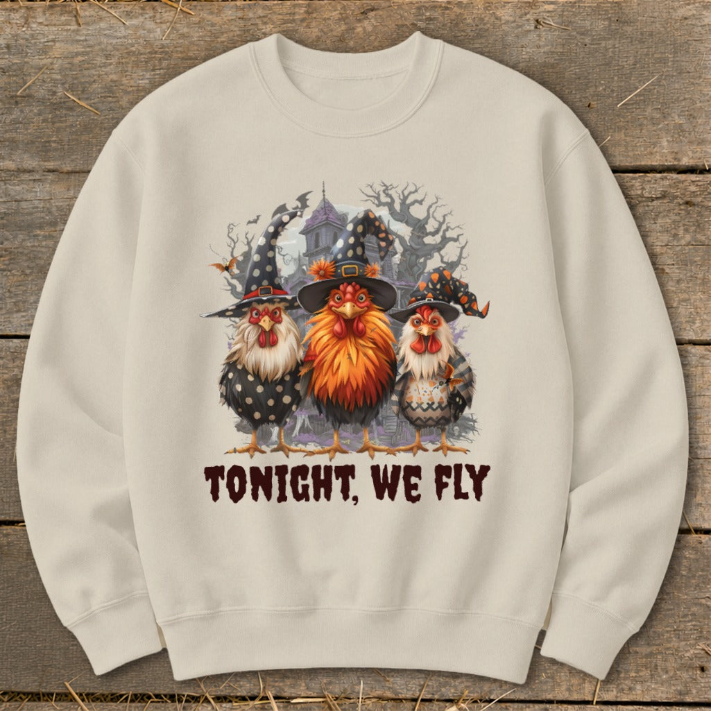 Three chickens in witch hats stand in front of a haunted house with the text "TONIGHT, WE FLY".