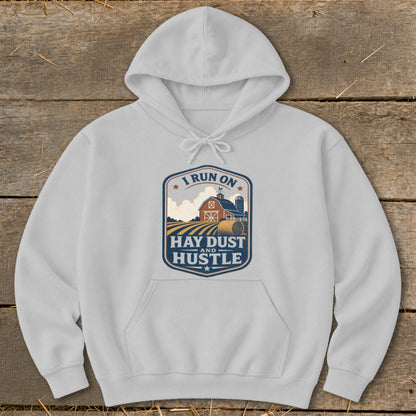 White hoodie with a rustic farm graphic and text "I Run on Hay Dust and Hustle."
